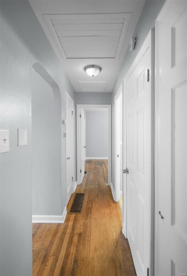 corridor with visible vents, wood-type flooring, baseboards, and attic access