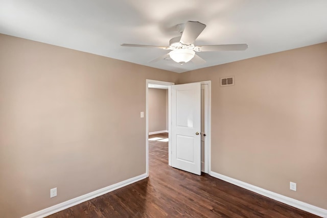 spare room featuring baseboards, visible vents, dark wood-style flooring, and ceiling fan