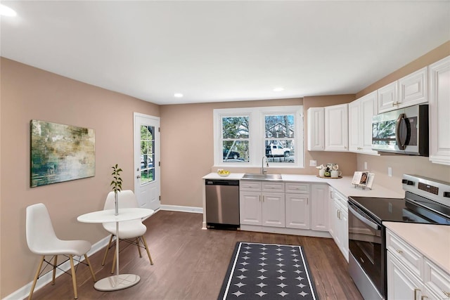 kitchen with stainless steel appliances, dark wood-type flooring, baseboards, and a sink