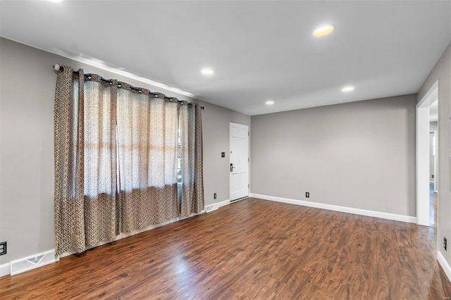 empty room with visible vents, baseboards, and wood finished floors