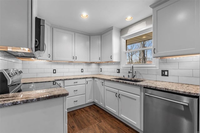 kitchen with a sink, stainless steel appliances, light stone countertops, and dark wood finished floors