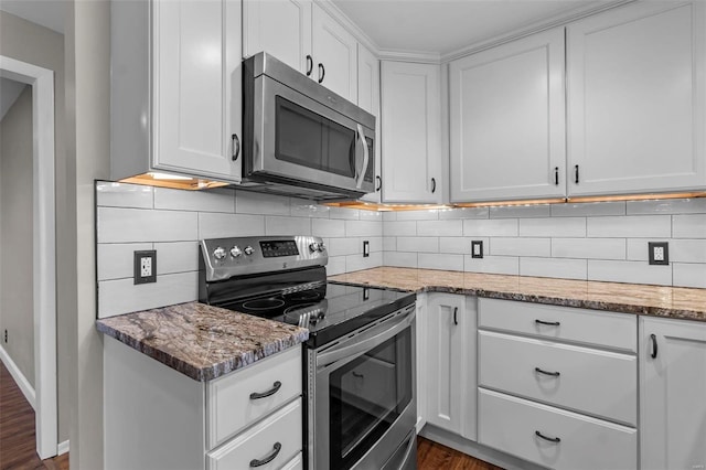 kitchen featuring dark wood-type flooring, light stone counters, white cabinetry, stainless steel appliances, and decorative backsplash