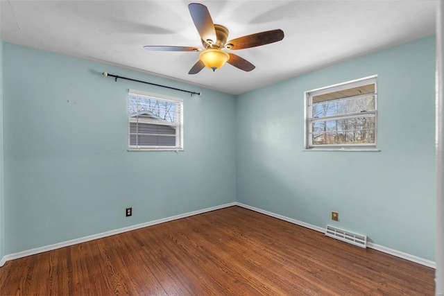 empty room with visible vents, baseboards, wood finished floors, and a ceiling fan