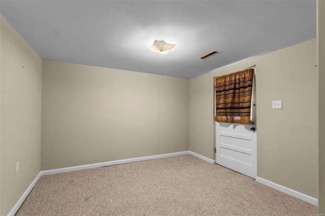 spare room featuring visible vents, light colored carpet, and baseboards