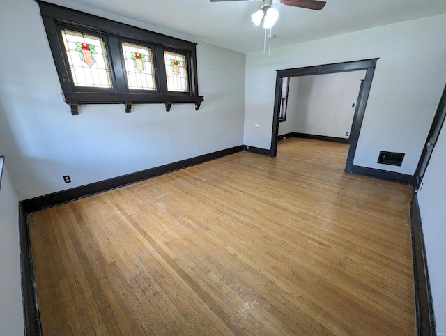 empty room featuring light wood-style flooring, visible vents, baseboards, and ceiling fan