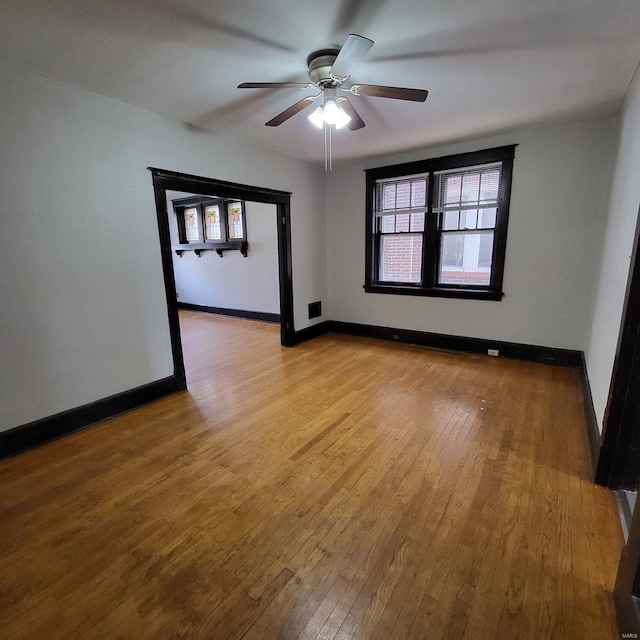 empty room featuring ceiling fan, baseboards, and wood-type flooring