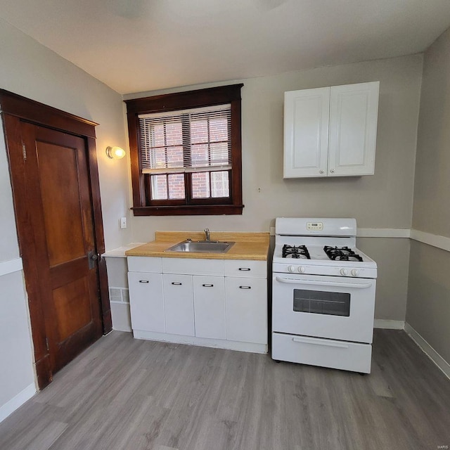 kitchen with white cabinetry, white gas range oven, light wood finished floors, and a sink