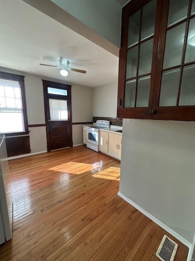 entrance foyer with ceiling fan, visible vents, baseboards, and wood finished floors