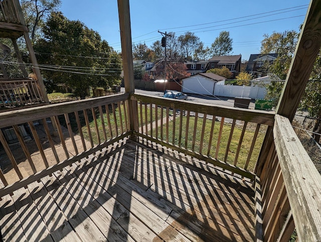 wooden terrace featuring a lawn, an outdoor structure, and fence