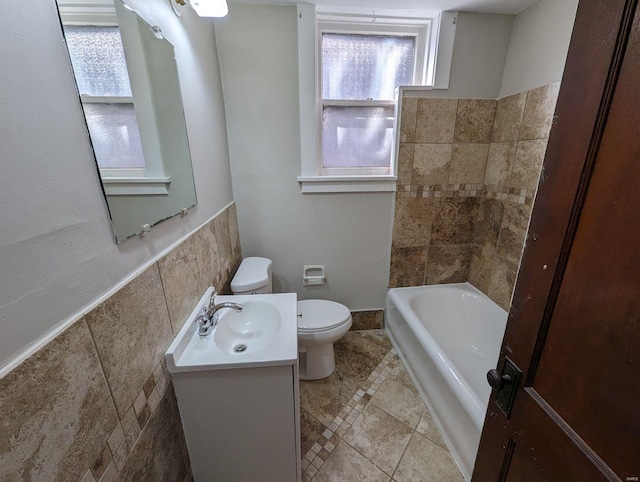 bathroom with vanity, tile walls, and toilet