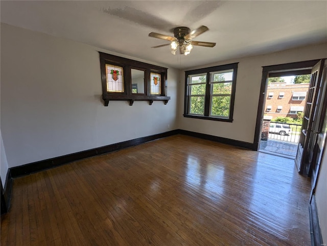 spare room with dark wood finished floors, baseboards, and a ceiling fan