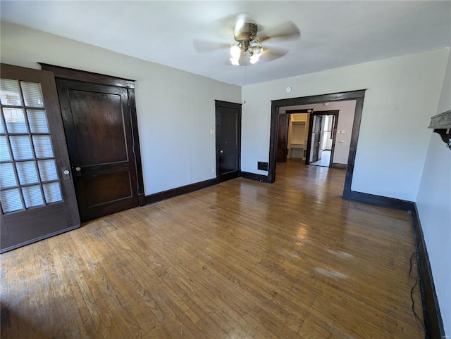 unfurnished room featuring a ceiling fan, baseboards, and wood-type flooring