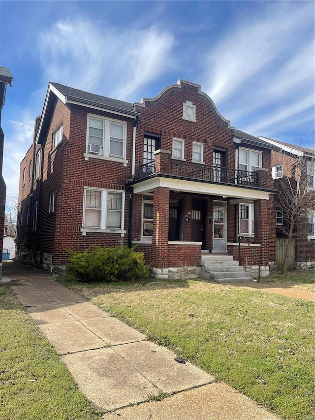 view of front of home featuring brick siding, a balcony, and a front lawn