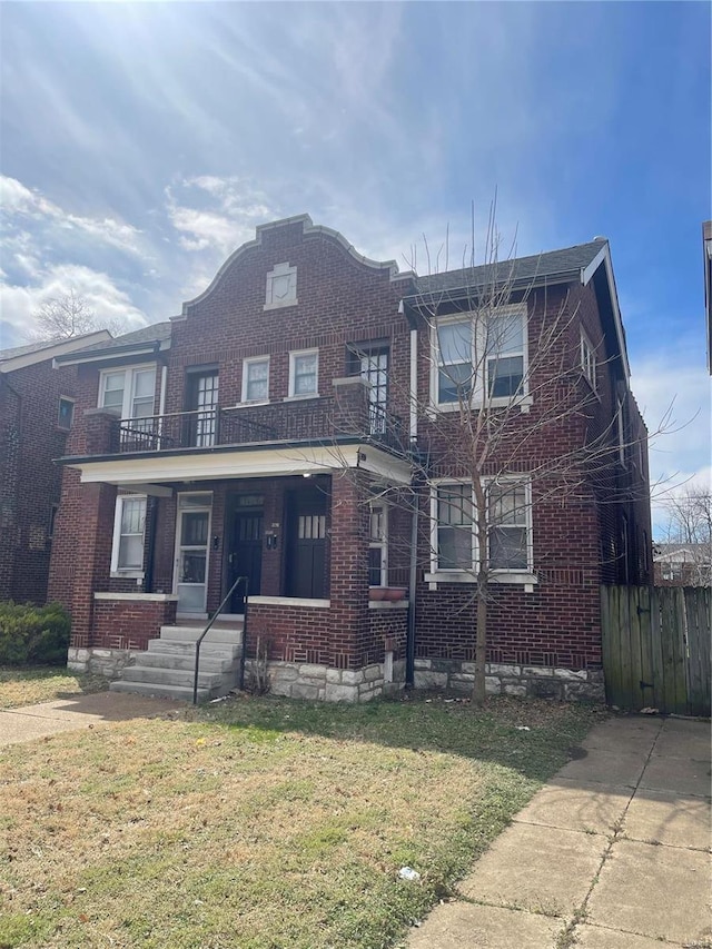 view of front facade featuring brick siding, a balcony, a porch, and a front yard