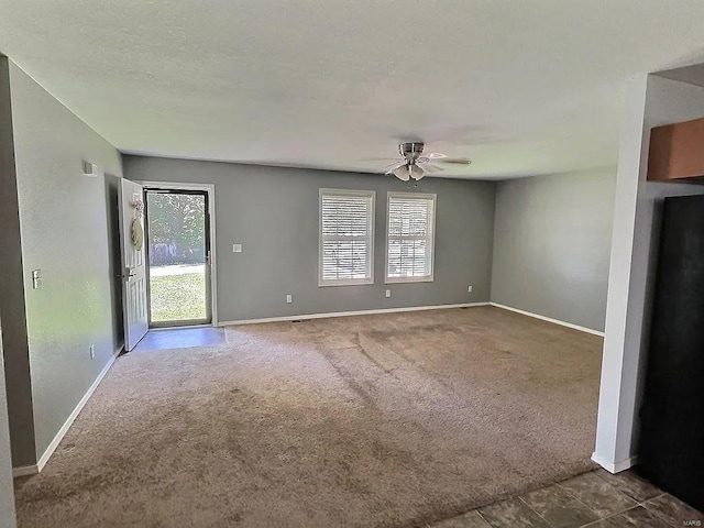 unfurnished living room with baseboards, plenty of natural light, a ceiling fan, and carpet flooring