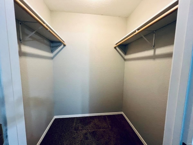 spacious closet featuring dark carpet