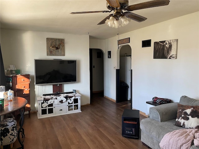 living room featuring baseboards, arched walkways, wood finished floors, and a ceiling fan