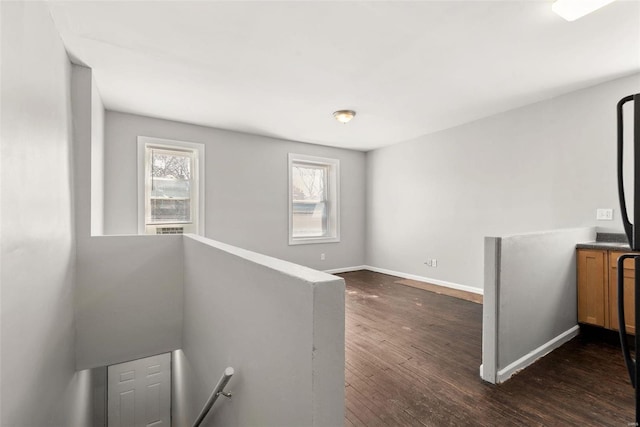 interior space with an upstairs landing, dark wood finished floors, and baseboards