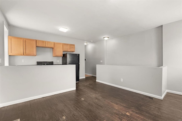 kitchen with light brown cabinets, baseboards, dark wood finished floors, light countertops, and freestanding refrigerator