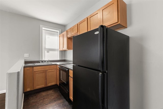 kitchen with a sink, dark countertops, black appliances, and dark wood-style flooring