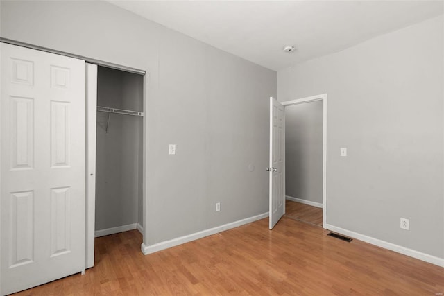 unfurnished bedroom featuring a closet, visible vents, light wood-type flooring, and baseboards