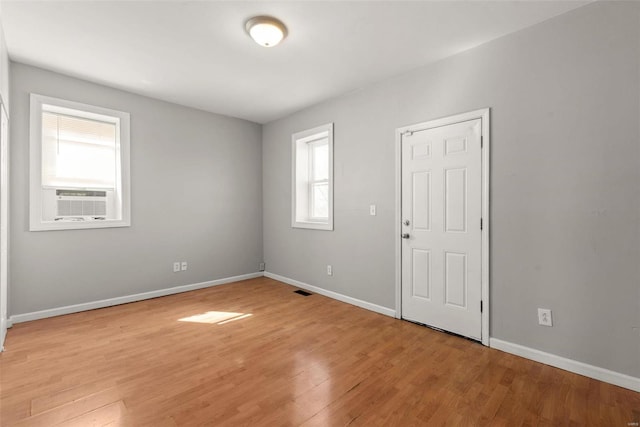 spare room featuring cooling unit, light wood-style floors, and baseboards