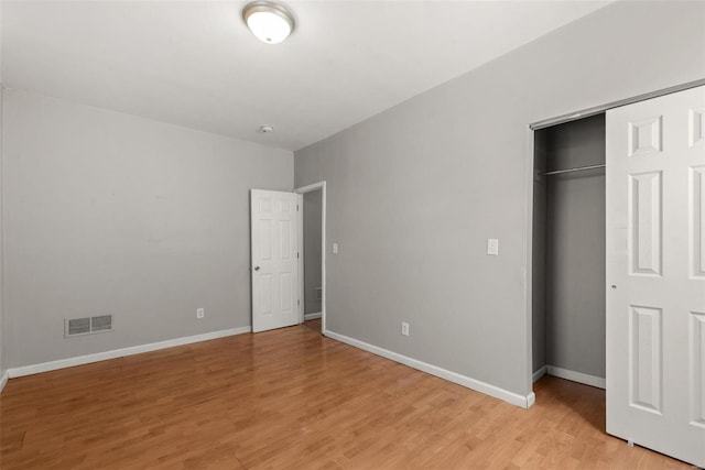 unfurnished bedroom with baseboards, visible vents, a closet, and light wood-type flooring