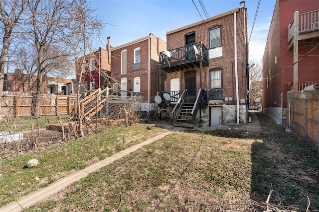 back of property featuring a balcony, fence, and brick siding