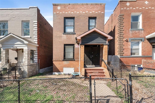 view of front facade featuring a fenced front yard, brick siding, and a gate