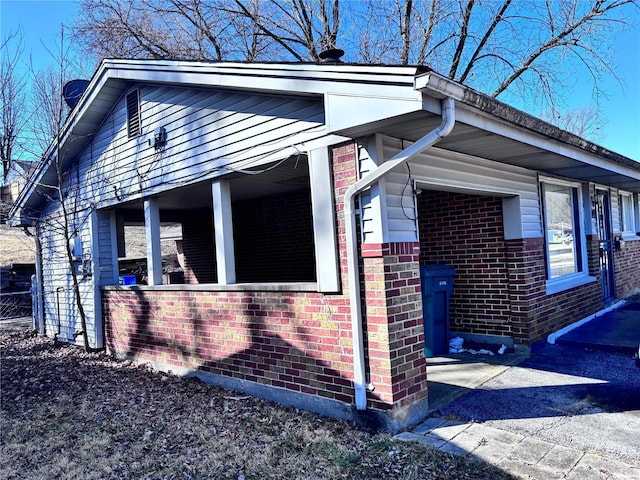 view of side of property with brick siding and covered porch