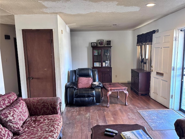 living area with visible vents, a textured ceiling, and hardwood / wood-style floors