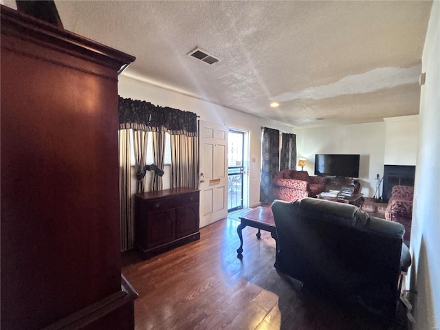 office area with visible vents, a textured ceiling, wood finished floors, and a fireplace