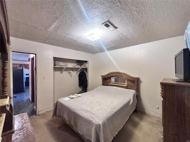 bedroom with carpet, a closet, freestanding refrigerator, and a textured ceiling