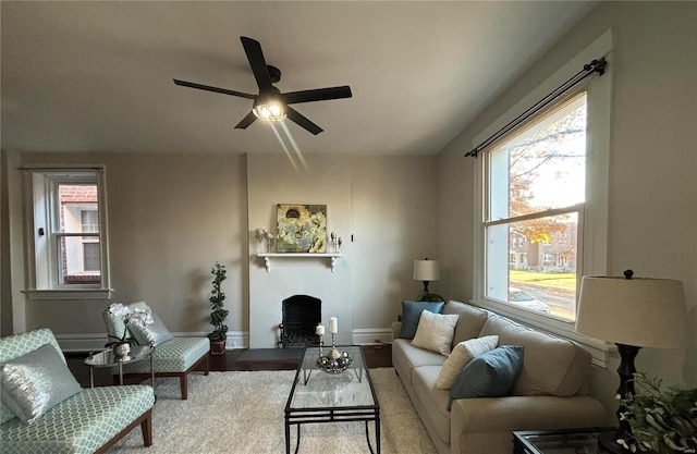 living room with wood finished floors, baseboards, a fireplace, and a ceiling fan