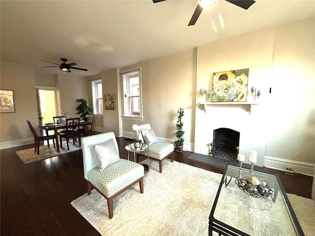 living room with a fireplace with flush hearth, baseboards, a ceiling fan, and wood finished floors