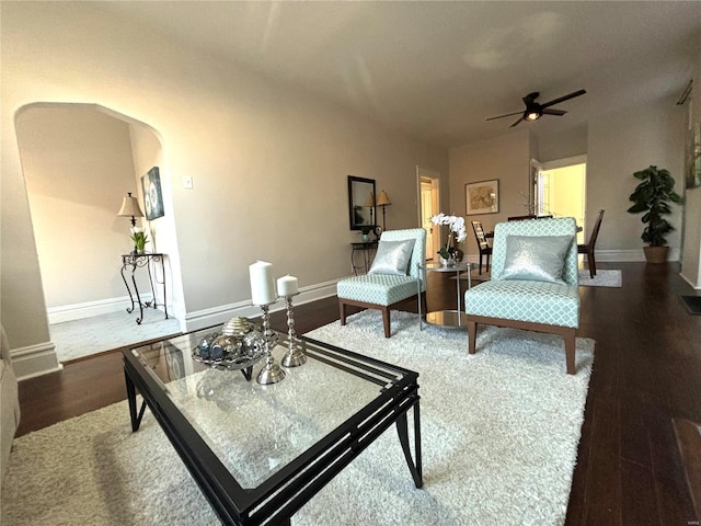 living area with arched walkways, baseboards, ceiling fan, and wood finished floors