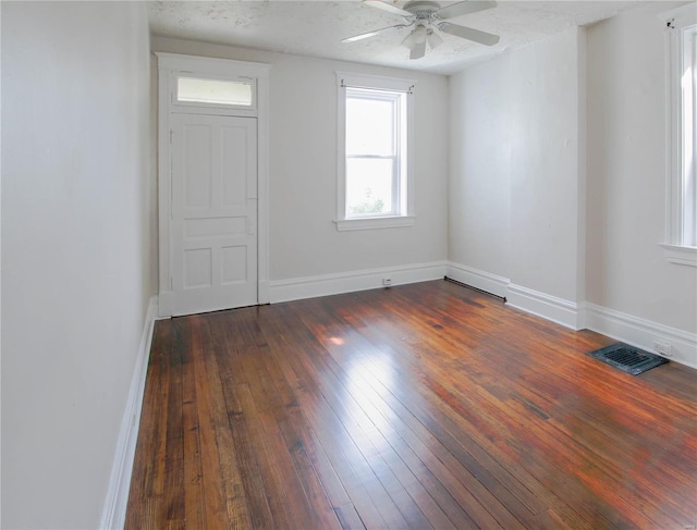 spare room featuring baseboards, visible vents, ceiling fan, dark wood-type flooring, and a textured ceiling