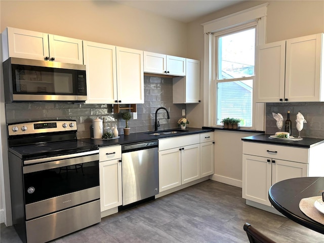 kitchen featuring dark countertops, white cabinets, appliances with stainless steel finishes, and a sink