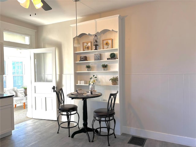 dining area with visible vents, a wainscoted wall, and a ceiling fan