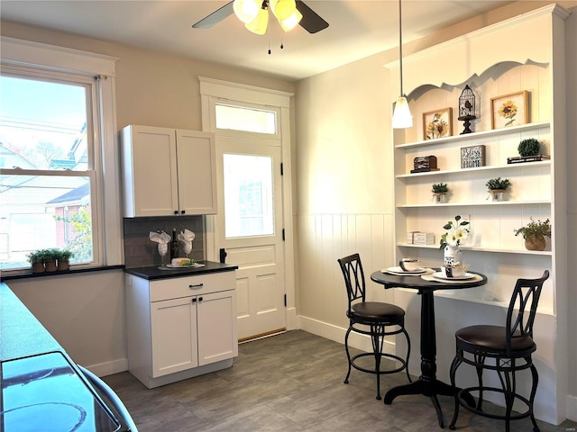 dining space with a wainscoted wall and ceiling fan