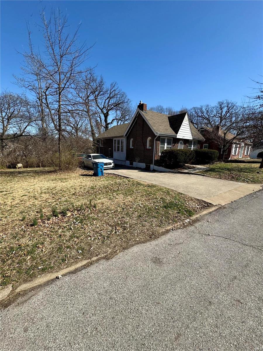 view of front facade with concrete driveway and a chimney