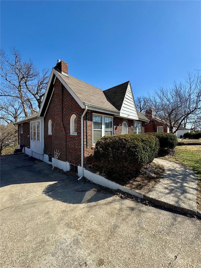 view of side of property featuring brick siding and a chimney