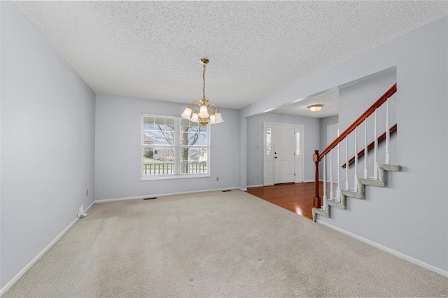 interior space with carpet flooring, a textured ceiling, baseboards, and an inviting chandelier