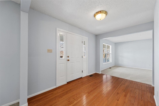 foyer with baseboards, wood-type flooring, and a textured ceiling