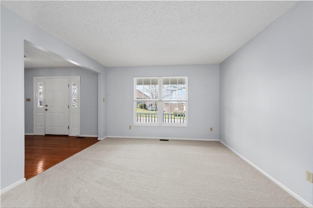 interior space featuring baseboards, carpet floors, a textured ceiling, and visible vents