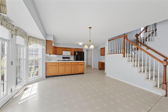 kitchen featuring brown cabinets, freestanding refrigerator, light countertops, baseboards, and white microwave