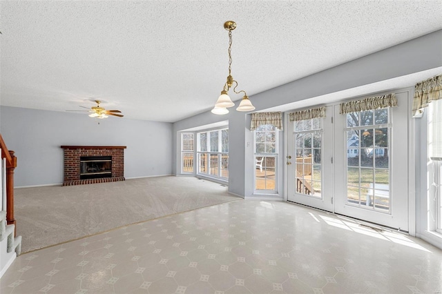 unfurnished living room with ceiling fan, a fireplace, a textured ceiling, and carpet