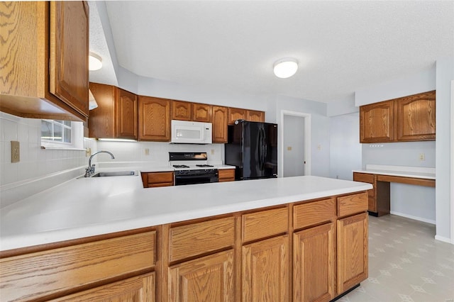 kitchen featuring a sink, gas range oven, freestanding refrigerator, light countertops, and white microwave