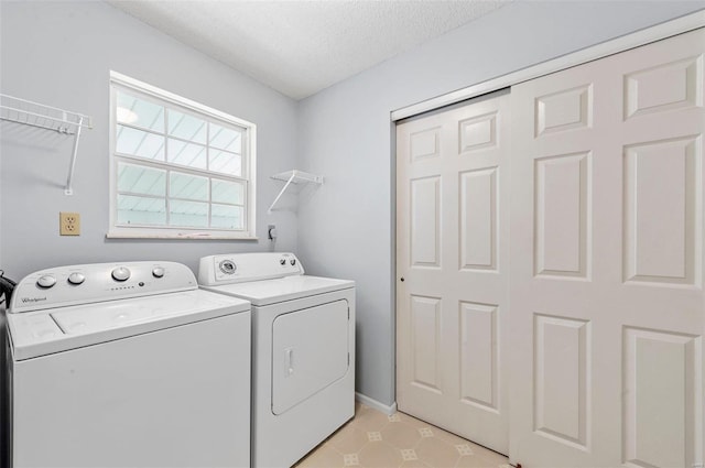 clothes washing area featuring laundry area, washer and dryer, a textured ceiling, and baseboards