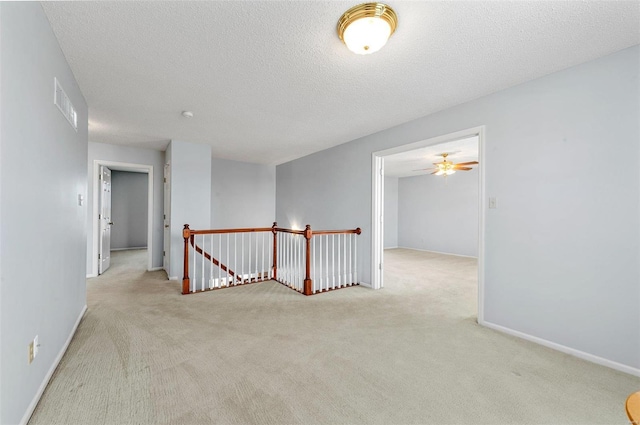 carpeted empty room featuring a ceiling fan, baseboards, visible vents, and a textured ceiling